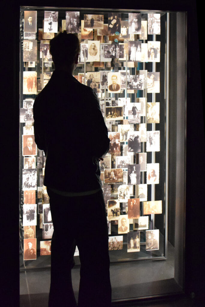 One person standing in front of several old black and white pictures exposed in the museum