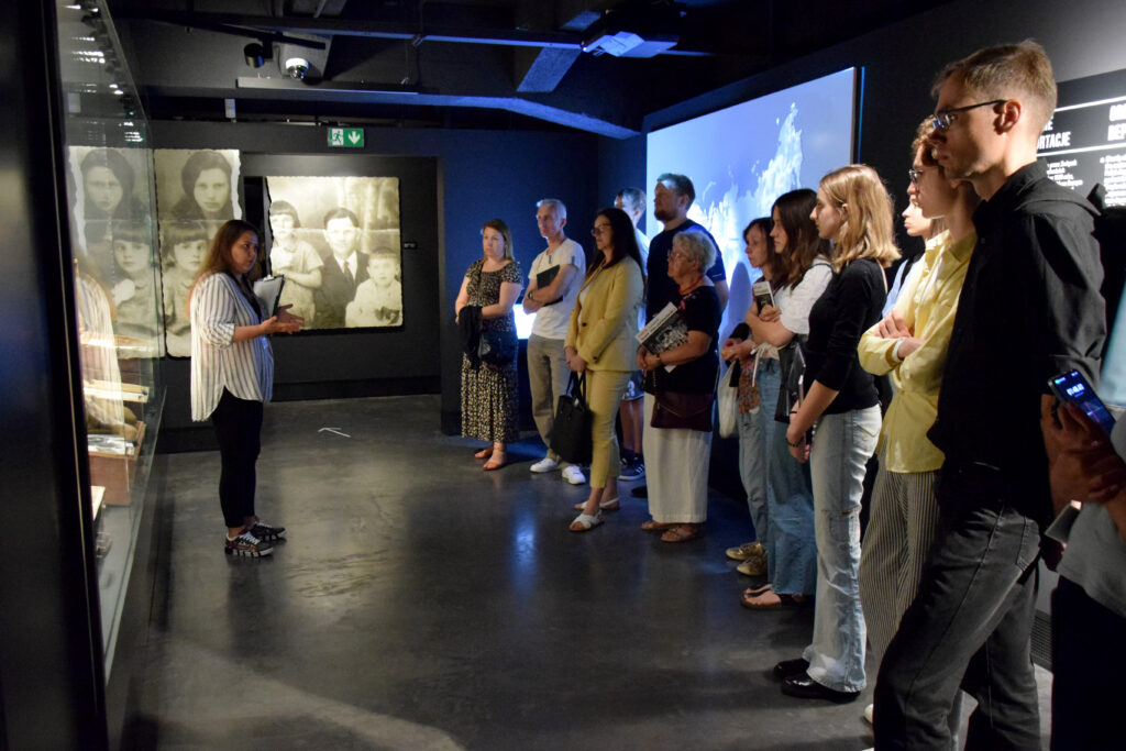 A group of people listening to a guide in a room of the museum