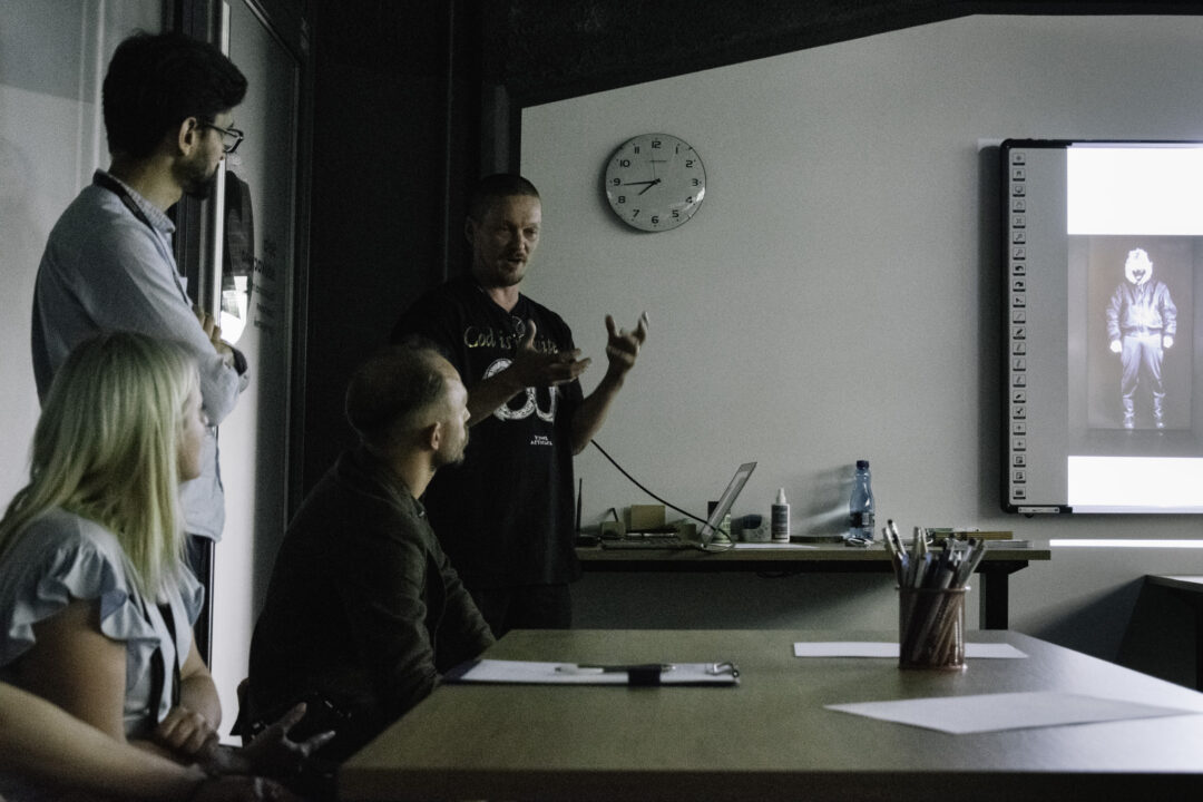 Artist Juhana Moisander talking to a group of people in a conference room